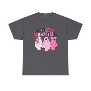 Op de afbeelding: Donkergrijs T-shirt met een afbeelding van drie cartoongeesten in roze en wit. De geesten houden een telefoon, een boek en een muis vast. De tekst "MEAN GHOULS" staat boven de geesten in een roze en zwart blokletterontwerp.