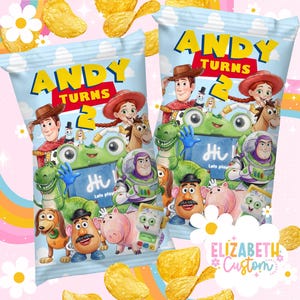 Puede incluir: Dos bolsas de snacks azul claro con personajes de Toy Story como Woody, Buzz Lightyear, Jessie, Rex y el Sr. Patata. El texto dice ANDY TURNS 2 y Hi! Let's play. Las bolsas est&aacute;n decoradas con patatas fritas amarillas y flores blancas.