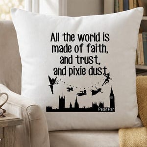 May include: A white cushion featuring the quote "All the world is made of faith, and trust, and pixie dust" in black. The design includes silhouettes of fairies and London landmarks, inspired by Peter Pan.