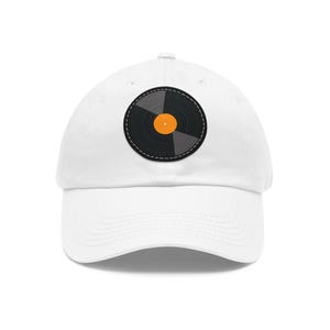 May include: A white baseball cap with a black and grey vinyl record design and an orange centre. The record is stitched onto the cap, providing a stylish accessory for music enthusiasts.