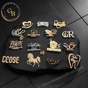 Puede incluir: Una colección de pines de solapa de metal dorado con varios diseños, incluyendo un caballo, un diente, una casa, estetoscopios y texto estilizado. Cada pin tiene un acabado metálico e incluye un cierre para sujetar a las prendas.