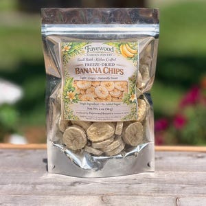 May include: A clear, resealable plastic pouch filled with freeze-dried banana chips. The label reads Fayewood Garden Pantry, Small-Batch Kitchen Crafted, Freeze-Dried Banana Chips, Light-Crispy-Naturally Sweet, Single Ingredient, No Added Sugar, Net Wt. 2 oz (56 g).