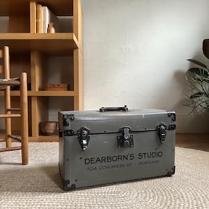 May include: A vintage gray metal suitcase with black hardware and the text "Dearborn's Studio 704 Congress St. Portland" printed on the front.