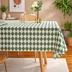 May include: A green and white diamond pattern tablecloth covers a wooden table. The tablecloth is draped over the table, with the pattern clearly visible. A vase of flowers and a decorative horse figurine are on the table.