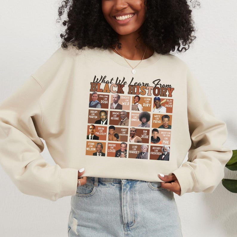 May include: Cream-colored sweatshirt with the text "What We Learn From Black History" in black and brown. The design includes portraits of historical figures like Rosa Parks, Martin Luther King Jr., and Maya Angelou. A stylish and educational apparel item.