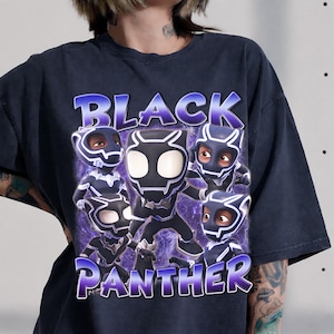 May include: A charcoal gray t-shirt featuring a graphic print of four stylized Black Panther characters in masks. The text "BLACK PANTHER" is printed in large, bold, purple-outlined letters above and below the characters against a purple nebula background.