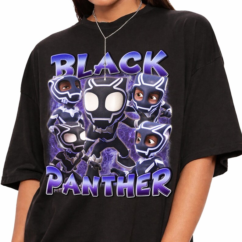 May include: A black short-sleeve t-shirt featuring a graphic print of five stylized Black Panther characters in masks. The text "BLACK PANTHER" is printed in large, bold, purple and blue gradient lettering above and below the characters.