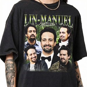May include: A black short-sleeved t-shirt featuring a graphic print of Lin-Manuel Miranda in five different poses and outfits. The text LIN-MANUEL is printed in a large, stylized green font at the top, with the name Miranda in a smaller white script font.