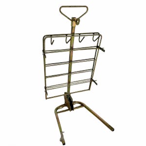 May include: A metallic gold-toned display rack featuring a vertical central support, a triangular top handle, and a rectangular grid frame with four hooks at the top. The base consists of two extending legs, providing a stable structure for hanging items.