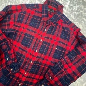 May include: A long-sleeve button-down shirt featuring a red and navy blue plaid pattern. The shirt has a standard collar, a front button placket, and buttoned cuffs. A black label inside the collar reads "High Grade by Pendleton".