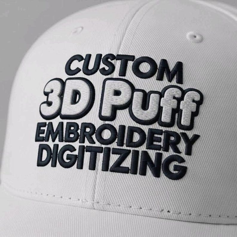 May include: A white baseball cap with the words "CUSTOM 3D Puff EMBROIDERY DIGITIZING" embroidered in black and white. The text is in a bold, puffy font, creating a 3D effect. The cap is made of a textured fabric.