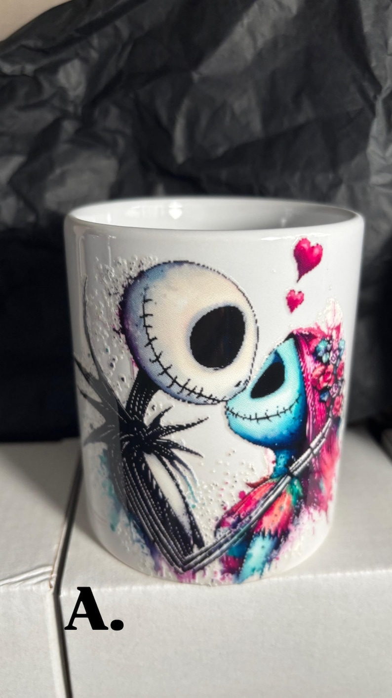 May include: White ceramic mug featuring a colorful illustration of Jack Skellington and Sally from The Nightmare Before Christmas. The design includes hearts and a romantic embrace, perfect for fans of the movie.
