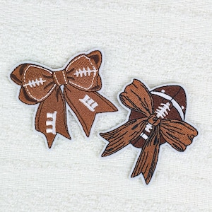 May include: Two brown football-themed bow patches. The bows are embroidered with white stitching to resemble a football. One bow is a traditional bow shape, and the other is a bow wrapped around a football.