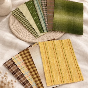 May include: A collection of rectangular fabric swatches arranged in two fan-shaped stacks. The top stack features various shades of green with plaid, polka dot, and striped patterns. The bottom stack includes yellow, brown, and cream fabrics with plaid, grid, and wavy line designs.