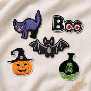 May include: A set of five embroidered patches featuring a purple cat, the text Boo with red eyes, a black bat, an orange pumpkin wearing a black witch hat, and a black potion bottle with a green skull and crossbones design on a white fabric.