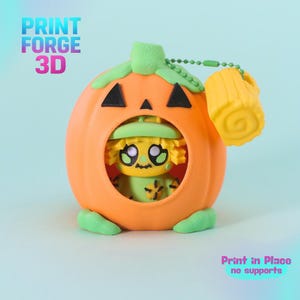May include: A 3D printed orange pumpkin container with a green stem and base, featuring black triangular eyes and a circular opening. Inside sits a small yellow scarecrow figure with a green hat. A yellow cylindrical charm hangs from a green chain.