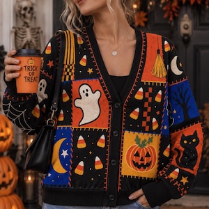 May include: A black V-neck cardigan featuring a patchwork pattern of Halloween motifs including white ghosts, orange pumpkins, black cats, yellow crescent moons, and candy corn. The knit sweater has a button-down front and ribbed cuffs.