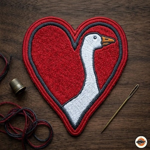 May include: Embroidered patch in the shape of a heart with a red background and a goose design. The goose is white with an orange beak and is set against a red heart with a gray border. A thimble, needle, and thread are also visible.