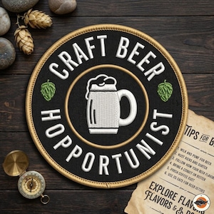 May include: A round black patch with the words "CRAFT BEER HOPPORTUNIST" in white, surrounding a white beer mug graphic. Two green hop graphics are on either side of the mug. The patch has a gold border.