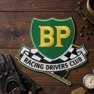 May include: Embroidered patch with a green shield design and the letters "BP" in gold. Below the shield is a banner with the words "RACING DRIVERS CLUB" and a checkered flag. The patch is on a wooden surface with a leather glove and a stopwatch.