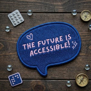 May include: A navy blue embroidered patch in a speech bubble shape with the text "THE FUTURE IS ACCESSIBLE!" in pink. The patch is surrounded by small glass marbles, a calculator, and two compasses.