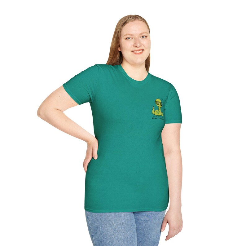 May include: Teal short-sleeved t-shirt with a small cartoon alien wearing glasses. The alien is yellow and green. The text "HAPPY PLANET" is below the alien. The shirt is being worn by a person.