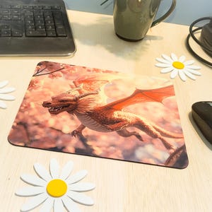 May include: A rectangular mousepad featuring a detailed illustration of a red dragon with outstretched wings, set against a backdrop of pink blossoms. The mousepad is surrounded by white daisy decorations and a black computer mouse.