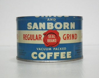 Op de afbeelding: Een blauwe en witte koffieblik met de tekst "Chase and Sanborn Regular Seal Brand Grind Vacuum Packed Coffee".