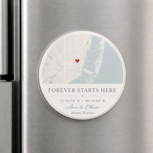 May include: A circular magnet featuring a light blue and white map of Miami, Florida, with a red heart icon. The text reads FOREVER STARTS HERE, the coordinates 25.76170° N | 80.19180° W, the names Ava & Ethan, and the location Miami, Florida.