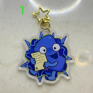 May include: A blue cartoon character keychain holding a paper with an "X" mark. The keychain has a gold star-shaped clasp and a clear, starburst-shaped border with blue and yellow accents. The number "1" is in the top left corner.