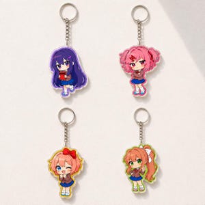 May include: Four acrylic keychains featuring chibi-style anime characters. Each charm displays a different character with distinct hair colors including purple, pink, peach, and orange, all wearing school uniforms with blue skirts and white socks.