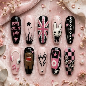 May include: A set of ten press-on nails featuring a black and light pink color palette. Designs include the text 'DONT CALL ME BABY', a Union Jack, a rabbit character, headphones, a brown creature, tribal art, a music player, and a heart charm.