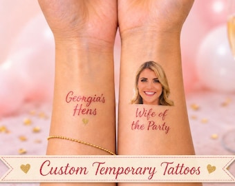 May include: Two temporary tattoos applied to skin. One tattoo features the red text Georgia's Hens with a small gold heart. The other tattoo displays a colour portrait of a smiling blonde person above the red text Wife of the Party.