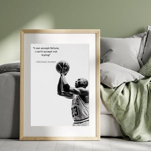 May include: Black and white framed print featuring Michael Jordan shooting a basketball. The print includes the quote "I can accept failure, I can't accept not trying" by Michael Jordan. The basketball player is wearing a jersey with the number 23.