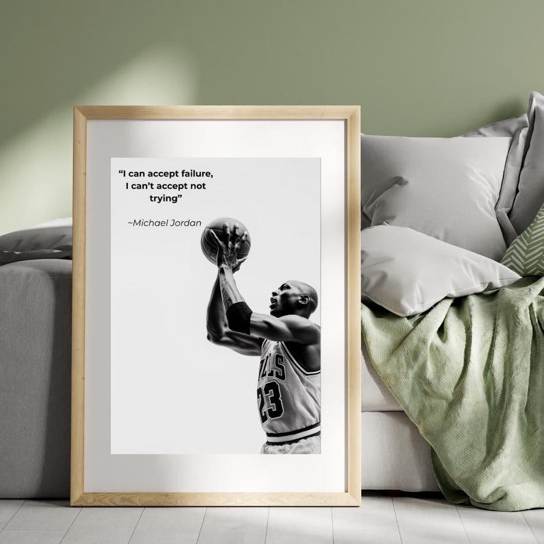 May include: Black and white framed print featuring Michael Jordan shooting a basketball. The print includes the quote "I can accept failure, I can't accept not trying" by Michael Jordan. The basketball player is wearing a jersey with the number 23.