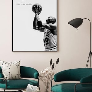 May include: Black and white framed print featuring Michael Jordan shooting a basketball. The print includes the quote "I can accept failure, I can't accept not trying" and the number 23 on his jersey. The print is displayed in a room with teal chairs.