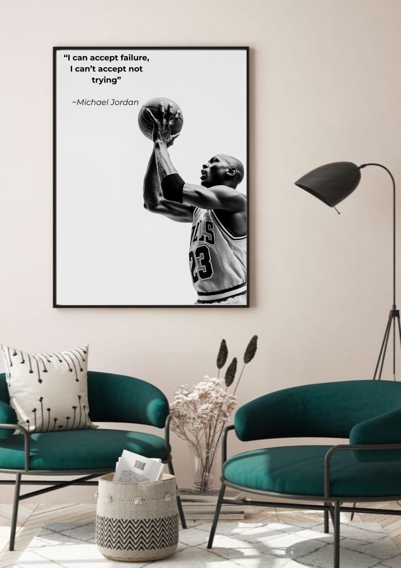 May include: Black and white framed print featuring Michael Jordan shooting a basketball. The print includes the quote "I can accept failure, I can't accept not trying" and the number 23 on his jersey. The print is displayed in a room with teal chairs.