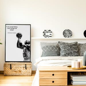 May include: Black and white framed print featuring Michael Jordan shooting a basketball, with the quote "I can accept failure, I can't accept not trying." The print is displayed above a woven storage trunk, with decorative plates and pillows in the background.