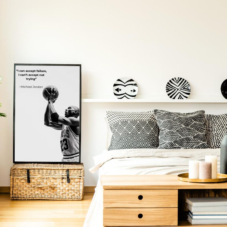 May include: Black and white framed print featuring Michael Jordan shooting a basketball, with the quote "I can accept failure, I can't accept not trying." The print is displayed above a woven storage trunk, with decorative plates and pillows in the background.