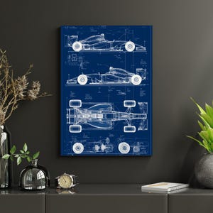 May include: A rectangular wall art print featuring a technical blueprint of a Formula One race car in white lines on a dark blue background. The design displays the vehicle from three distinct angles: side profile, top view, and a detailed chassis view.