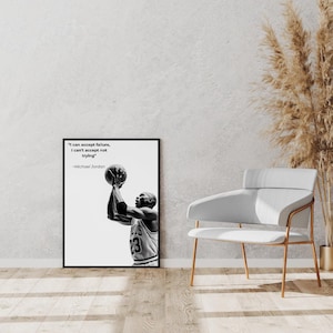 May include: Black and white framed print featuring Michael Jordan shooting a basketball. The print includes the quote "I can accept failure, I can't accept not trying" by Michael Jordan. The image is displayed on a wooden floor.