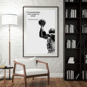May include: Black and white framed print featuring Michael Jordan shooting a basketball. The print includes the quote "I can accept failure, I can't accept not trying" by Michael Jordan. The image is displayed in a room with a chair, lamp, and bookshelf.