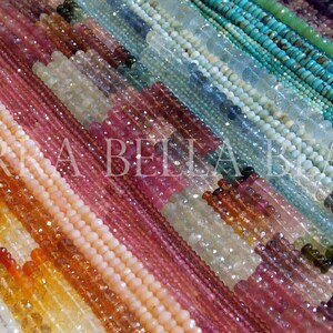 May include: A variety of gemstone beads in different colors and shapes, including pink, blue, green, and orange. The beads are arranged in rows, creating a colorful and textured pattern.  TERRA BELLABeads is visible in the image.