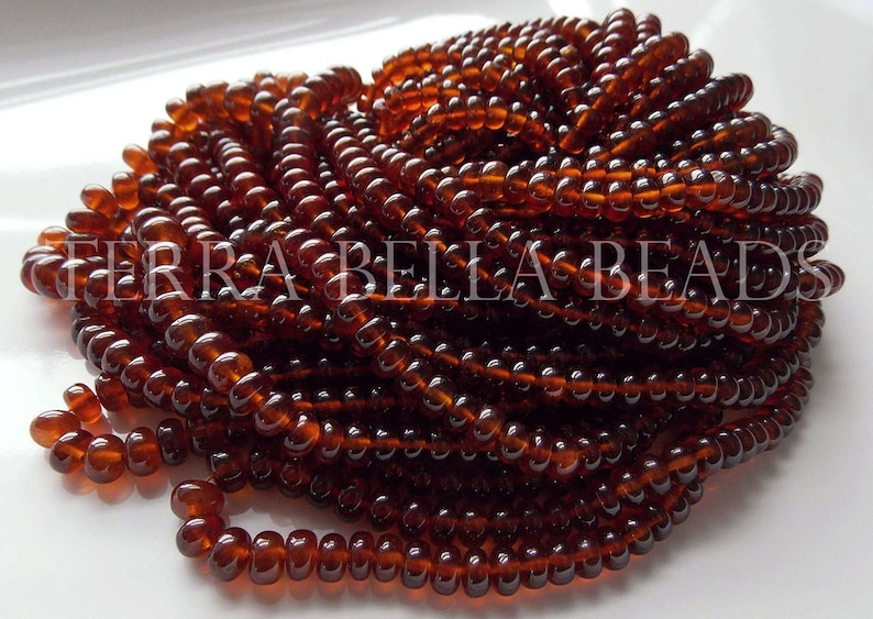 May include: A close-up of a pile of small, round, brown glass beads. The beads are arranged in a spiral pattern and have a glossy finish.
