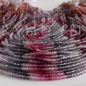 May include: A collection of multi-colored gemstone beads in shades of pink, gray, and clear. The beads are strung together, forming a dense, layered arrangement. The beads are small and round, and the overall effect is one of delicate beauty.