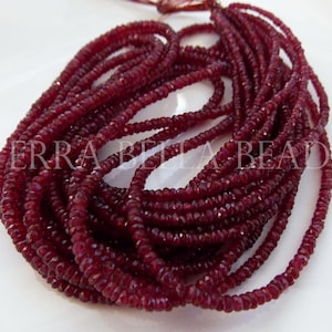 May include: A collection of deep red gemstone beads, possibly ruby, arranged in multiple strands. The beads are small, faceted, and have a rich, dark color. The image includes the text "TERRA BELLA BEADS".
