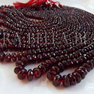 May include: A strand of deep red garnet beads, faceted and round, with a smooth, polished finish. The beads are strung on a thin cord and are approximately 4mm in diameter. The strand is approximately 16 inches long.