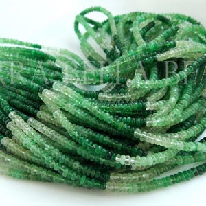 May include: A strand of green and clear glass beads. The beads are faceted and have a slightly irregular shape. The beads are strung on a clear thread.