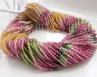 May include: A strand of multi-colored gemstone beads, including pink, green, and yellow. The beads are small and round, and they are strung together on a white thread.