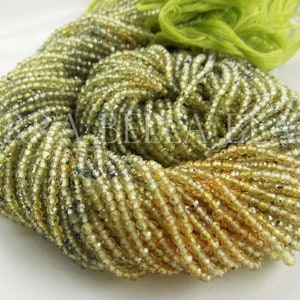 May include: A strand of light green and yellow faceted glass beads. The beads are small and round, and they have a shiny, iridescent finish.
